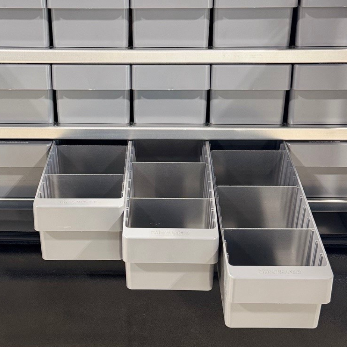 Set of gray storage bins on a black surface with a metal shelf in the background.