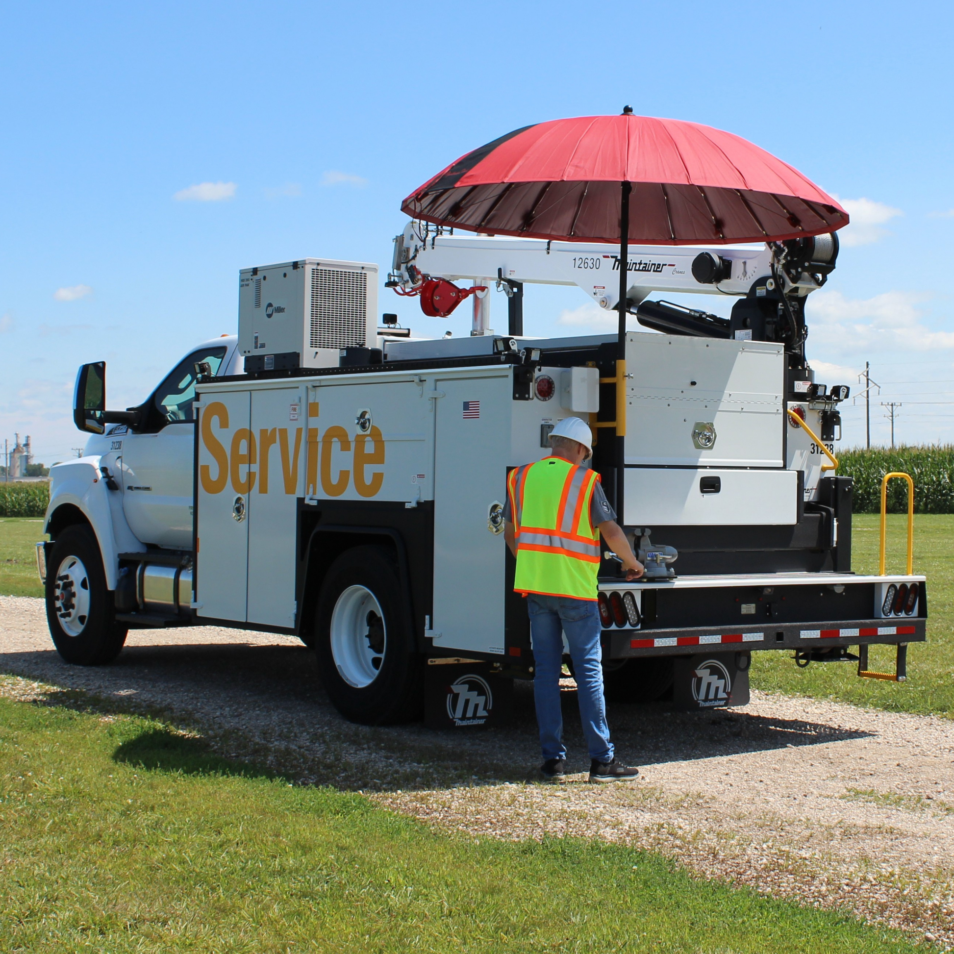 A large red umbrella attached to the back of a utility vehicle with person working.